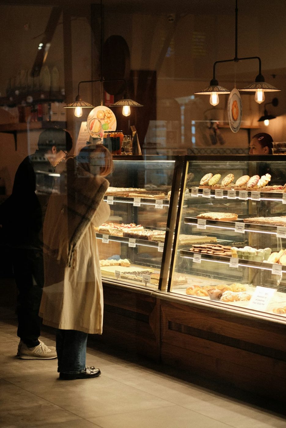 Customer browsing a lit bakery display case